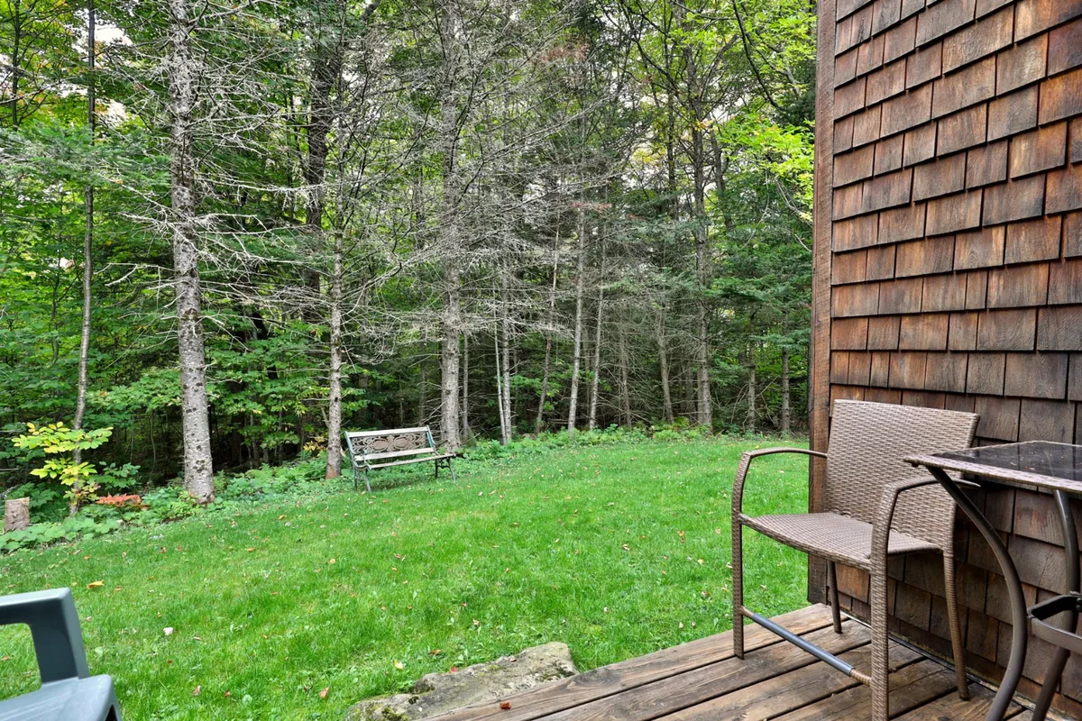 A peaceful patio area with a wooden bench, patio furniture, manicured lawn, and trees provides a tranquil setting for relaxing or socializing in nature. The space is inviting for unwinding after an active day outside.
