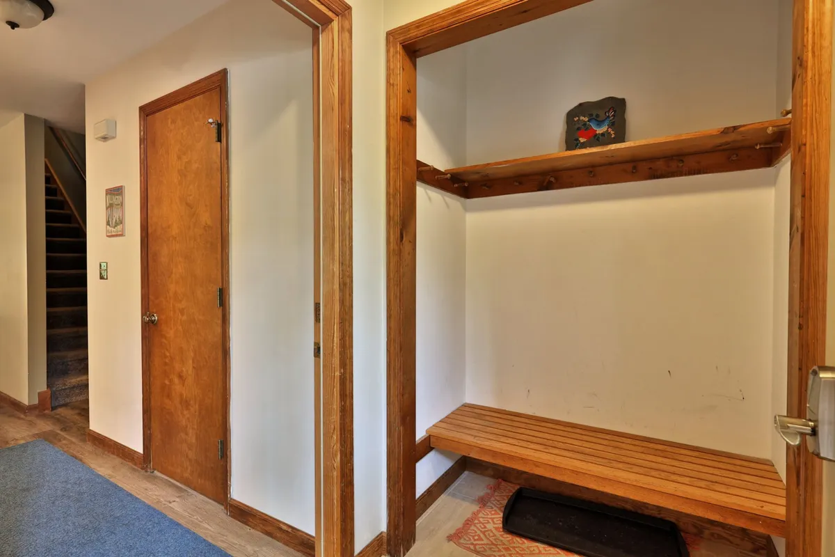 A welcoming entryway interior with a wooden bench, shelf, and door, designed for easy entry and exit. This area hints at practical features like smart lock access, shoe and coat storage, and first impressions of safety and comfort.